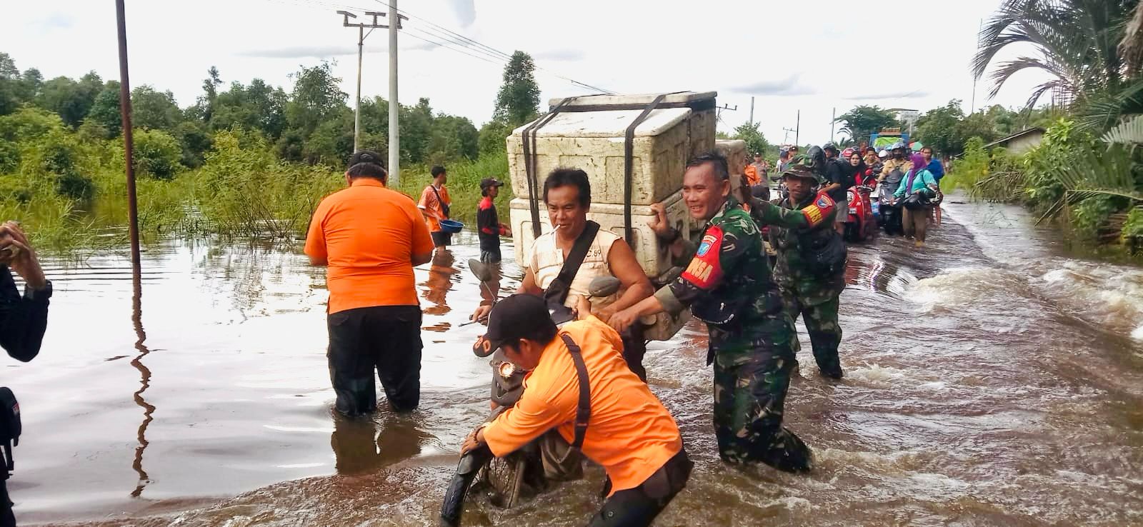 Sigap, Aksi Babinsa Koramil 1012 - 10/Dusun Selatan Bantu Warga Lewati Jalan Rusak Akibat Banjir
